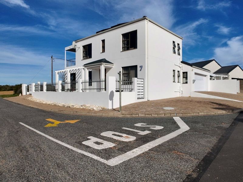 A well-maintained double-story residential property featuring a paved driveway, attached garage, perimeter fencing, and a balcony with a pergola.