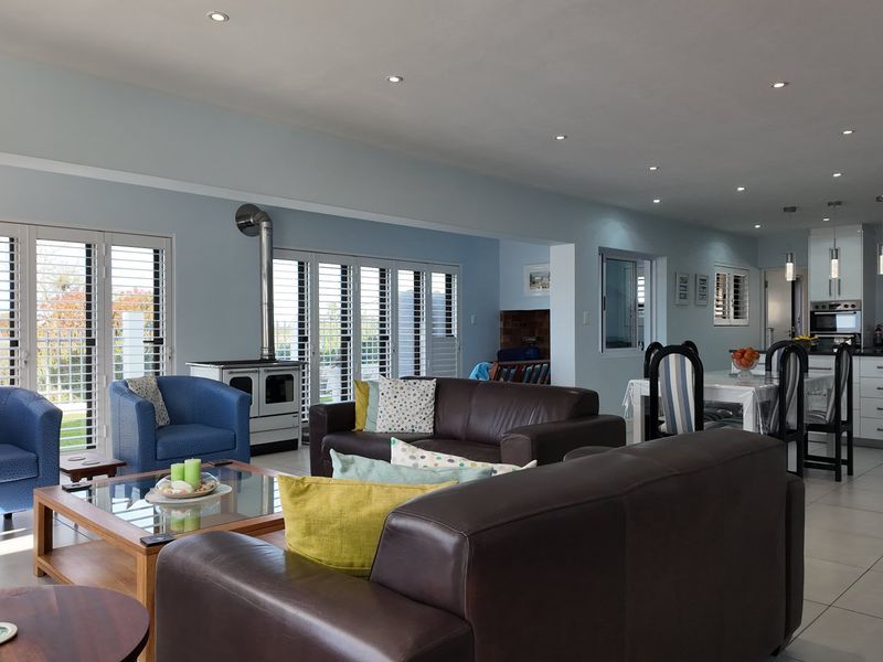 Spacious open-plan living and dining area featuring a modern kitchen with island, tiled floors, and large stacker doors leading to the outdoors.