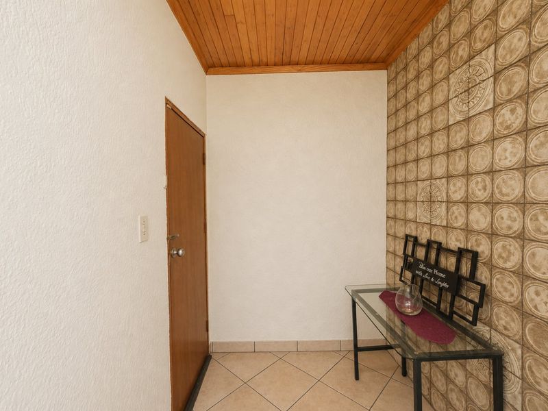 An entrance foyer featuring tiled flooring, a wooden ceiling, and a decorative tiled feature wall.