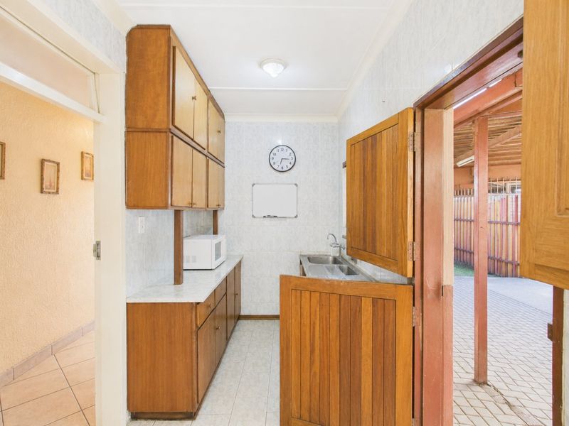 A functional scullery area featuring built-in wooden cabinetry, a double stainless steel sink, and a dutch door leading to the exterior.