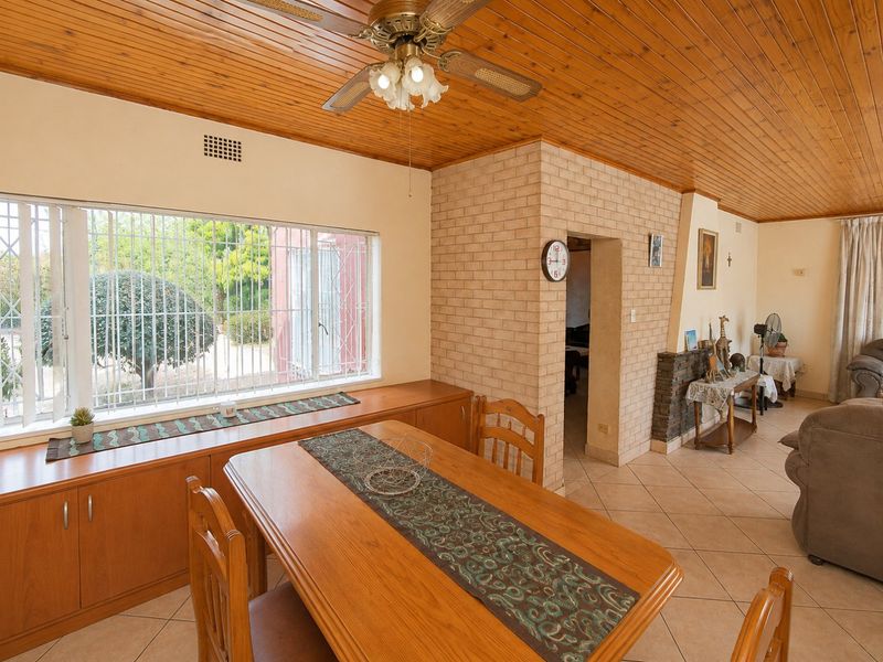 Dining area featuring timber ceiling, built-in cabinetry, tiled flooring, and a brick fireplace, offering a warm and functional space.