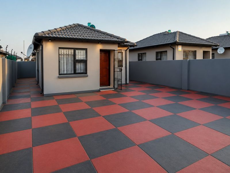 A well-maintained rear exterior view featuring a paved courtyard with a distinctive checkerboard pattern, perimeter walls, and a secure entrance.