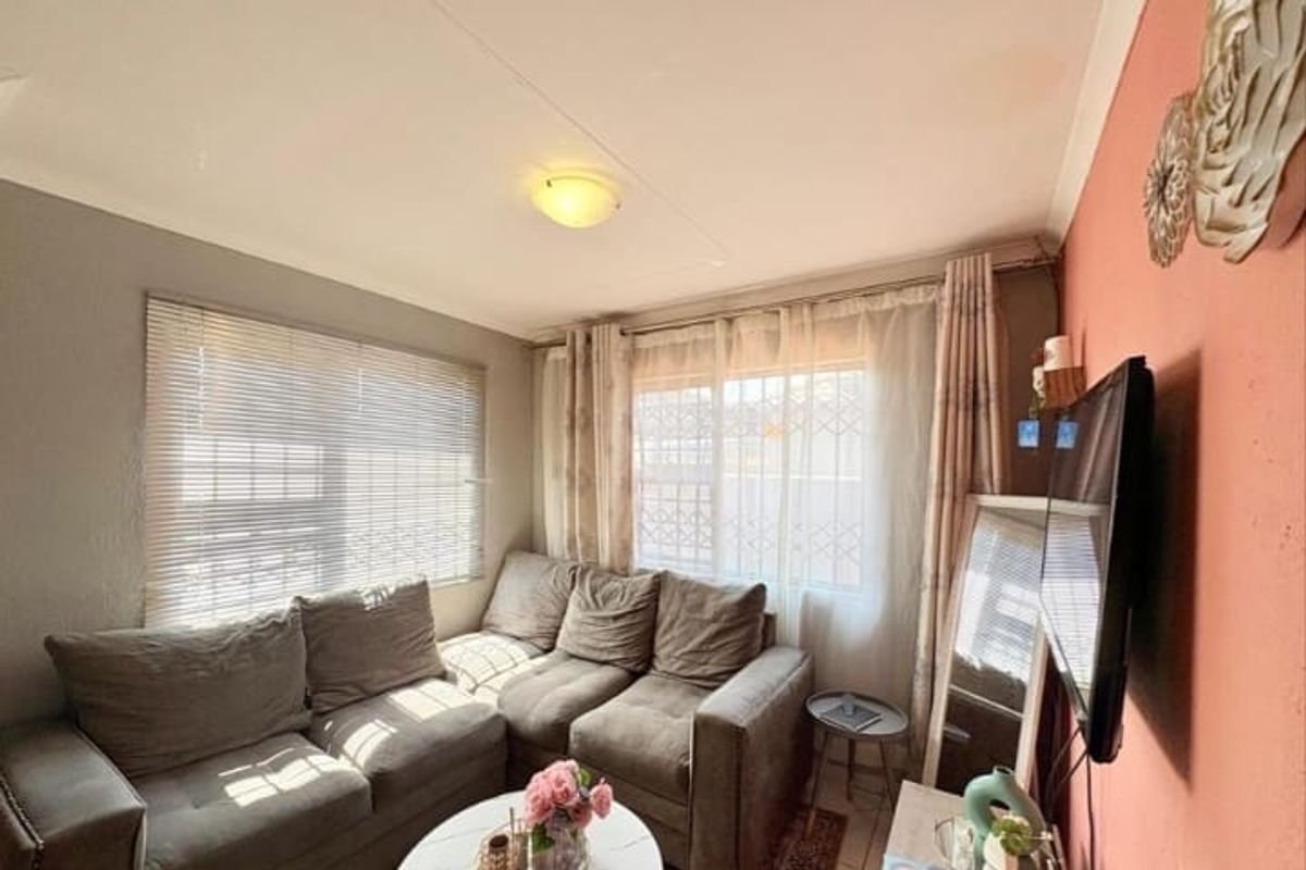 A compact living room featuring security bars on windows and neutral wall finishes, providing a functional and cozy space.