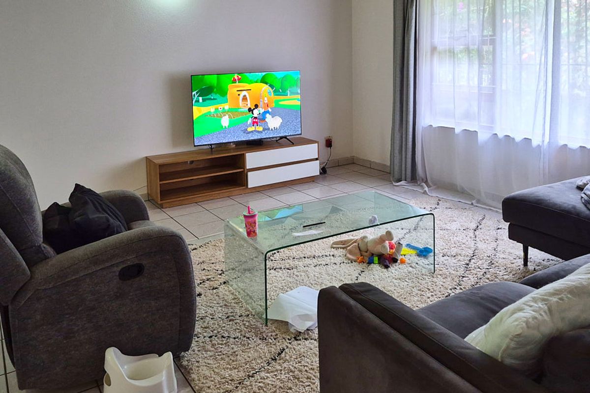 A comfortable living room featuring tiled flooring and a large window with natural light, providing a functional space for relaxation.