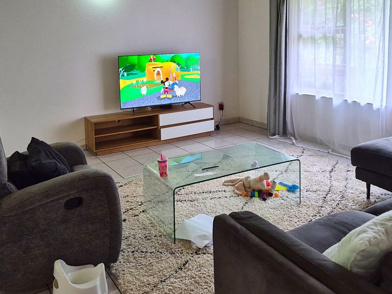 A comfortable living room featuring tiled flooring and a large window with natural light, providing a functional space for relaxation.