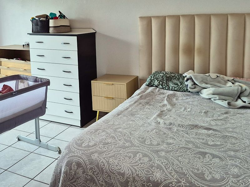 A bedroom featuring tiled flooring and a neutral wall finish, providing a functional space for rest.
