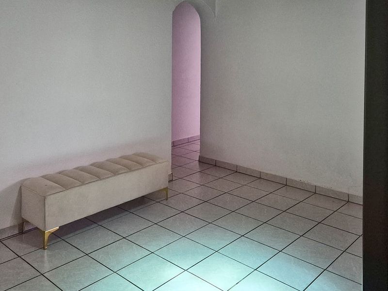 A simple hallway featuring ceramic tile flooring and an arched doorway leading to an adjacent room.