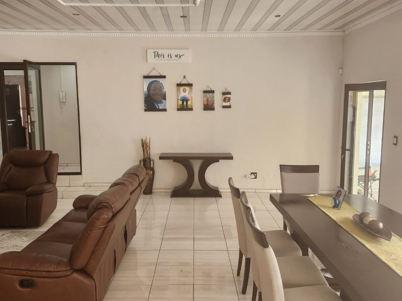 Spacious open-plan living and dining area featuring tiled flooring, decorative ceiling detailing, and direct access to the outdoors via a sliding glass door.