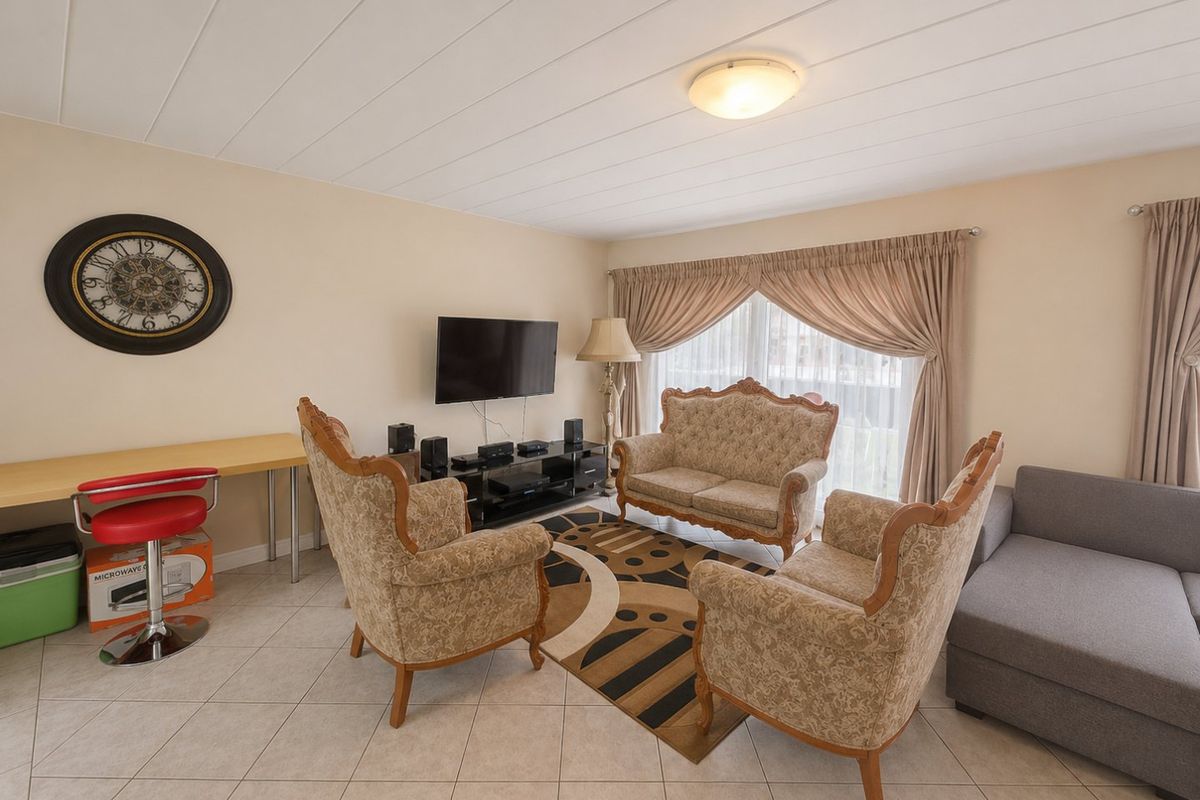 A comfortable living room featuring tiled flooring, panelled ceiling, and a sliding glass door providing natural light.