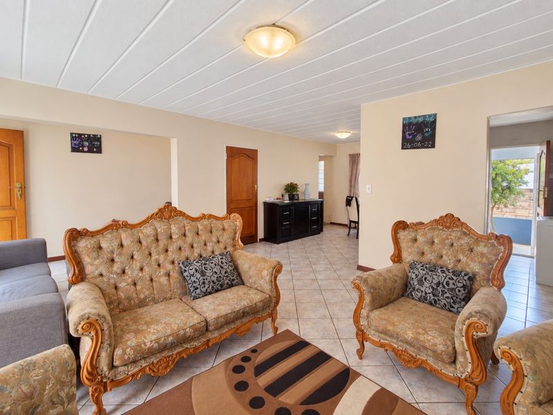 Spacious living area featuring neutral tiled flooring, a panelled ceiling, and direct access to adjacent rooms and outdoor space.