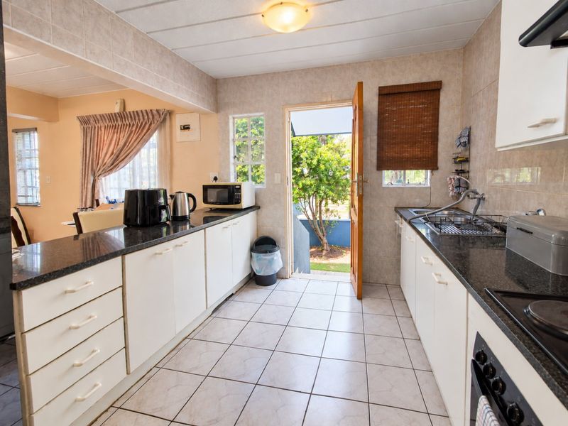 Functional kitchen featuring granite countertops, built-in cabinetry, and direct access to the exterior, offering a practical layout with tiled finishes throughout.