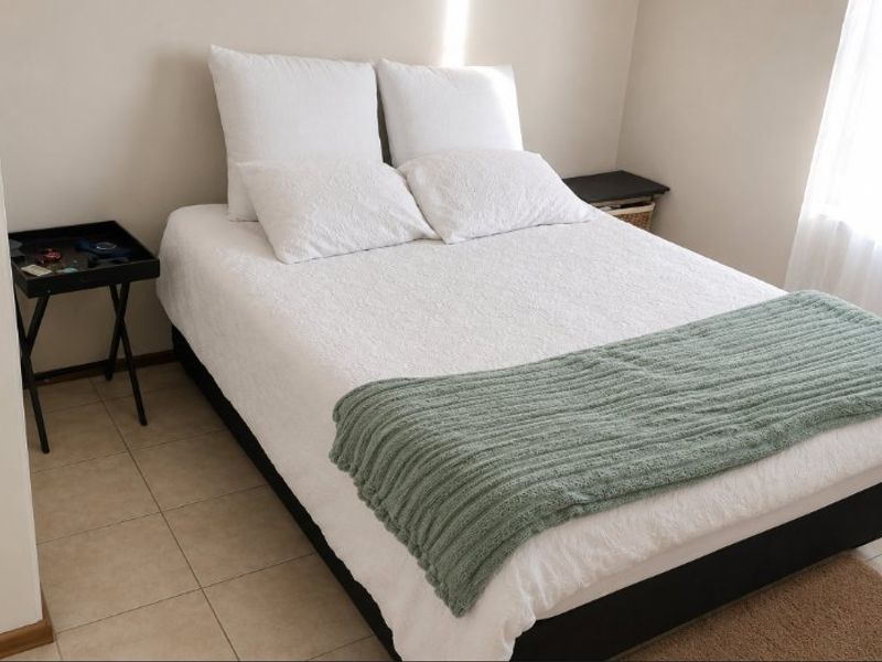 A simple bedroom featuring neutral wall tones and tiled flooring, providing a clean and functional space.