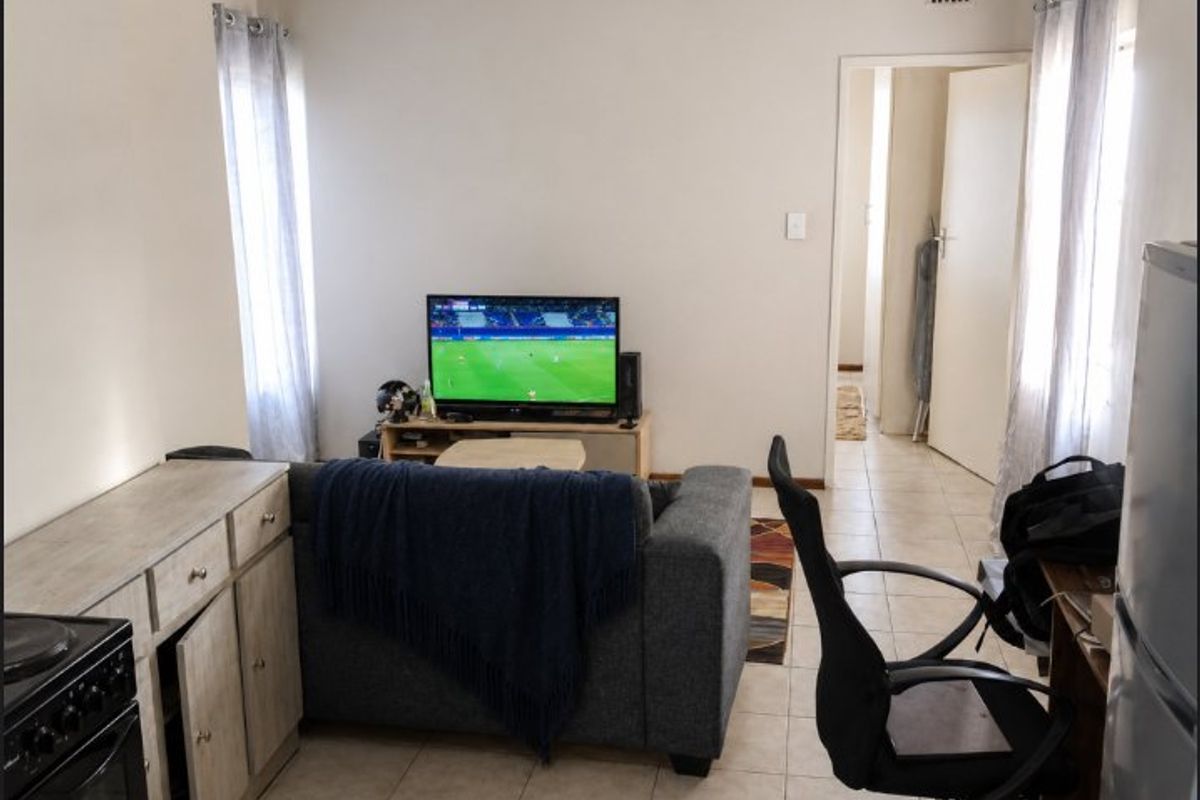 A functional living area featuring tiled flooring and built-in cabinetry, providing a practical space with direct access to the hallway.
