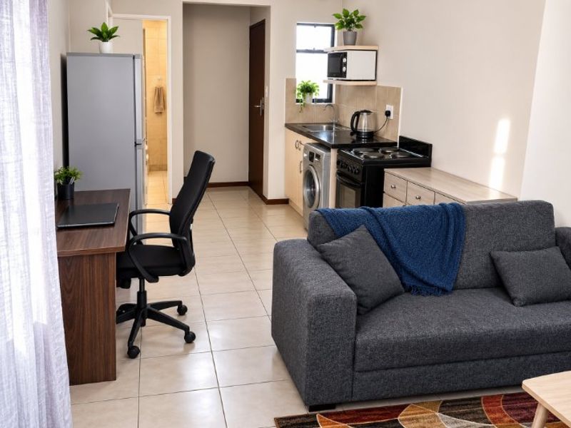 An open-plan living area featuring a compact kitchenette with built-in cabinetry, stove, and sink, seamlessly connected to the main living space.