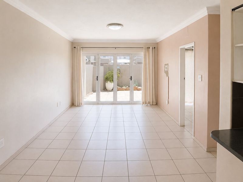 Bright open-plan living area featuring neutral tiled flooring, coving, and large sliding glass doors providing direct access to the rear patio.