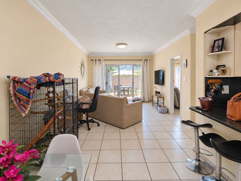 Open-plan living area featuring tiled flooring, crown molding, and a sliding glass door leading to an outdoor patio space.