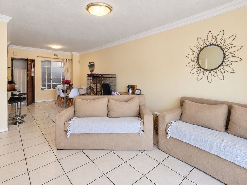 Open-plan living area featuring neutral tiled flooring, ceiling cornices, and flush mount lighting, providing a functional and versatile space for relaxation and dining.