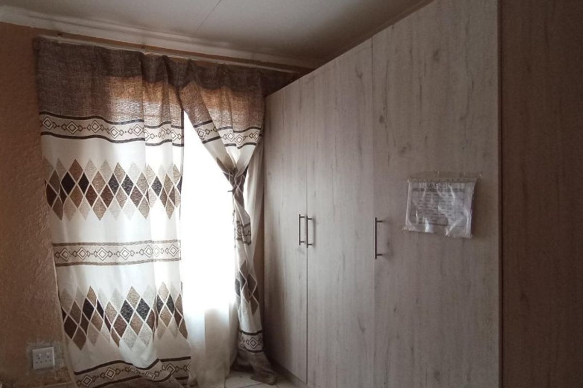Bedroom featuring a light wood-finish built-in wardrobe and natural light from the window.