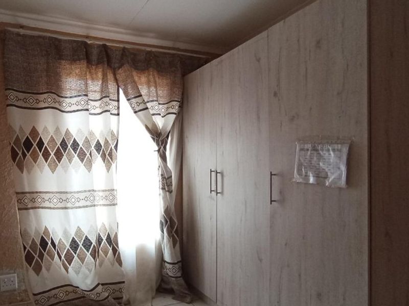 Bedroom featuring a light wood-finish built-in wardrobe and natural light from the window.
