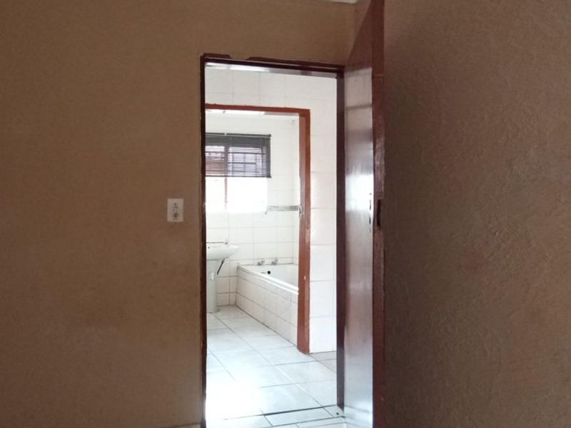 A view from a hallway looking into an adjacent bathroom featuring tiled floors and a built-in bathtub.