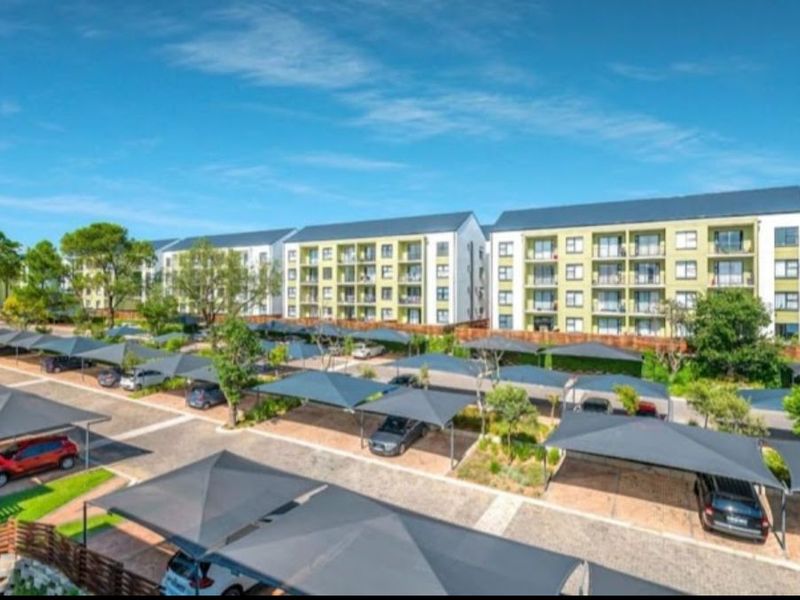 An elevated view of a modern apartment complex featuring multiple residential blocks, private balconies, and extensive covered parking bays for residents.