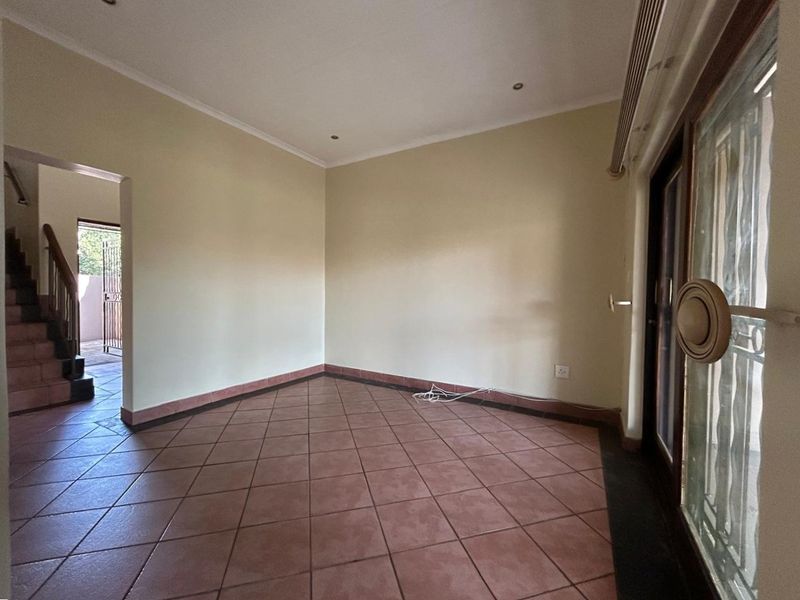 An empty living room featuring tiled flooring, recessed lighting, and a sliding glass door leading to an outdoor area.