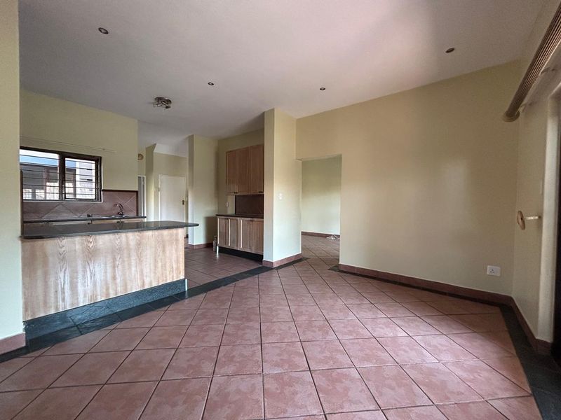 Spacious open-plan living and kitchen area featuring tiled flooring, granite countertops, and wooden cabinetry, offering a functional layout ready for modern updates.