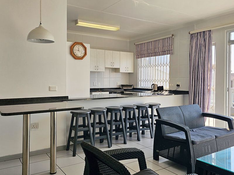 Open-plan living and kitchen area featuring granite countertops, tiled flooring, and direct access to a balcony through a sliding glass door.