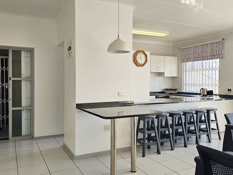 Open plan kitchen and living area featuring granite countertops, tiled flooring, and secure access points with security gates and bars.