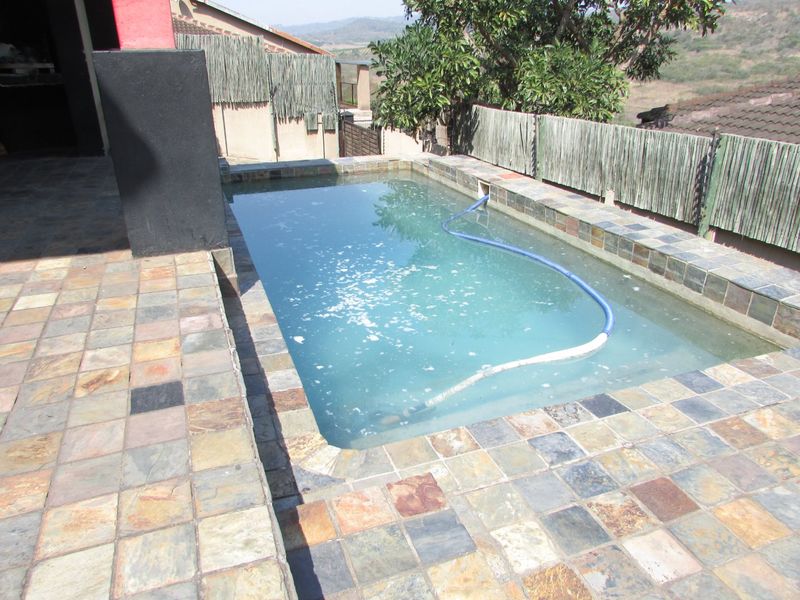 Outdoor swimming pool area featuring slate tile paving and reed fencing, requiring maintenance to the pool water and surrounding finishes.
