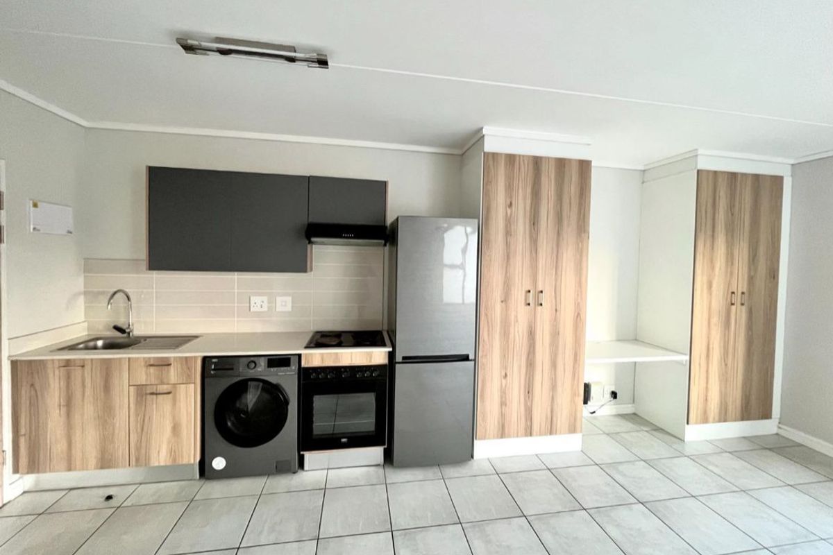 Modern kitchen featuring wood-finish cabinetry, integrated appliances, tiled flooring, and a functional layout with ample storage space.