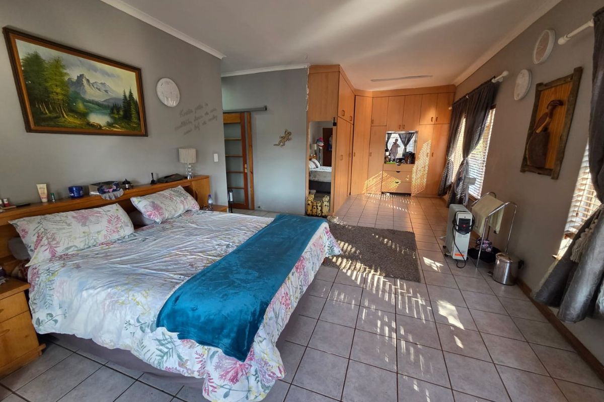 Spacious bedroom featuring extensive built-in wooden cabinetry, tiled flooring, and natural light through window blinds.