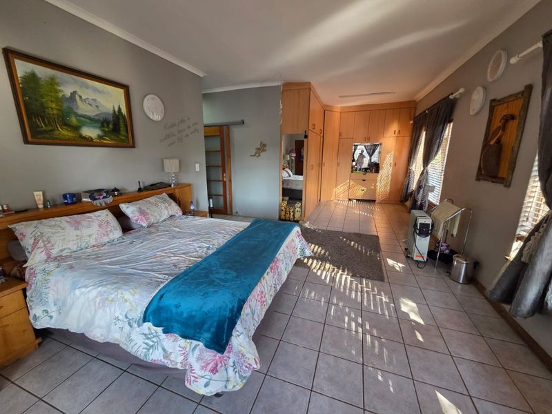 Spacious bedroom featuring extensive built-in wooden cabinetry, tiled flooring, and natural light through window blinds.