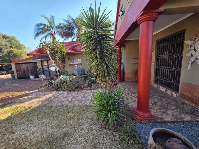 Front entrance area featuring a tiled patio, prominent red structural columns, and secure metal gate access to the home.