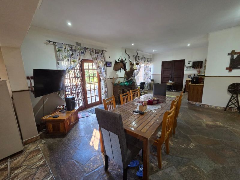 Spacious dining area featuring natural stone flooring, recessed lighting, and direct access to the exterior through a timber door with a security gate.
