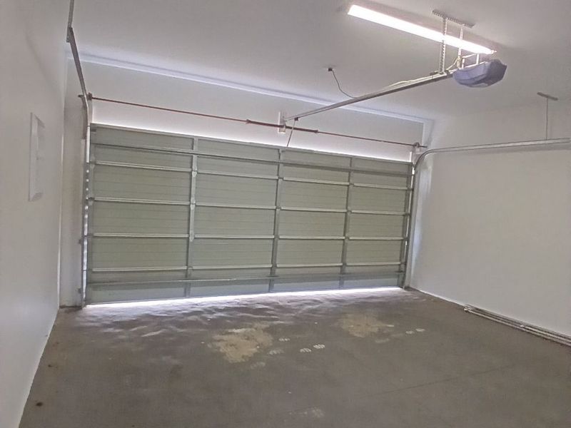 A clean, empty single-car garage featuring a sectional door, automatic opener, and concrete flooring.