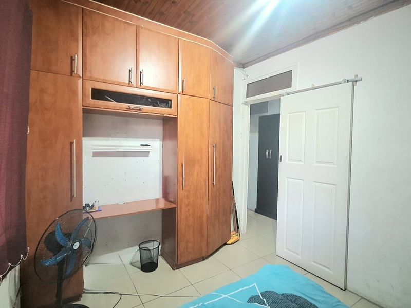 Bedroom featuring extensive built-in wooden cabinetry, tiled flooring, and a timber-paneled ceiling, offering functional storage space.