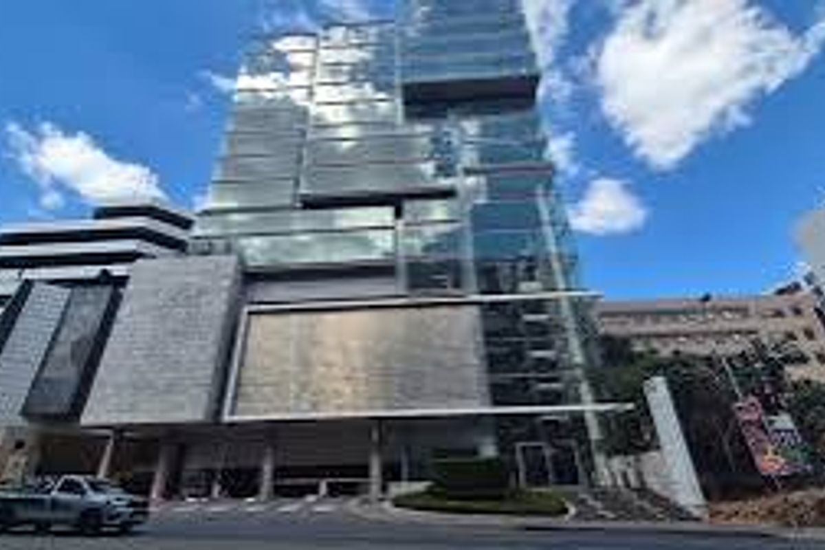 Modern commercial high-rise building featuring a contemporary glass facade, stone cladding, and a prominent street-level entrance.