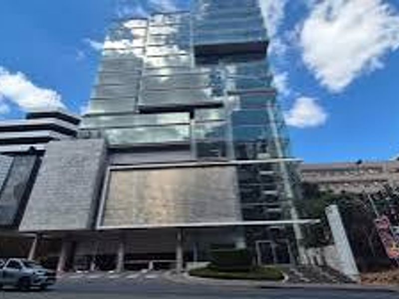Modern commercial high-rise building featuring a contemporary glass facade, stone cladding, and a prominent street-level entrance.