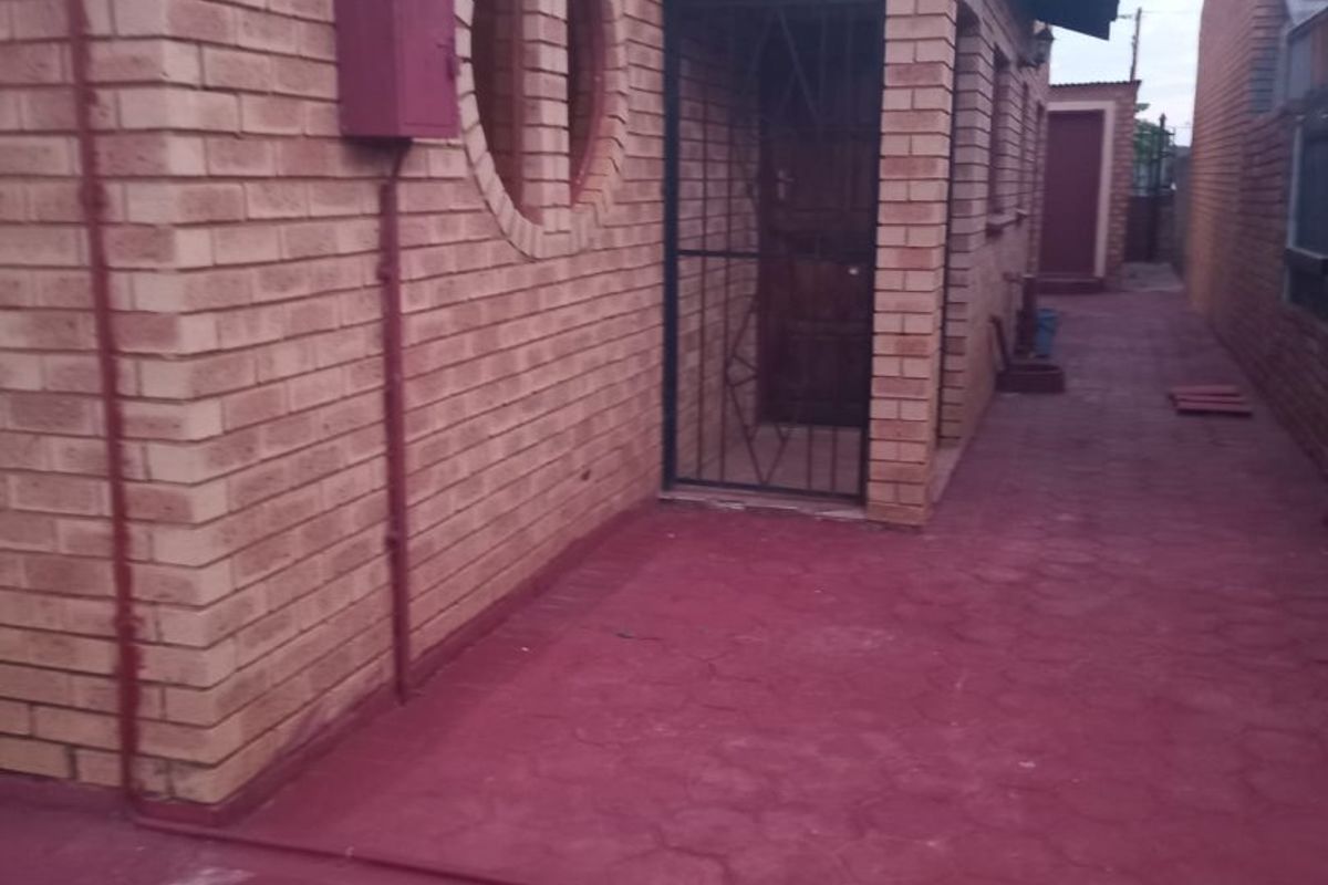A side view of the property featuring face brick walls, a circular window, a security gate, and a paved walkway.