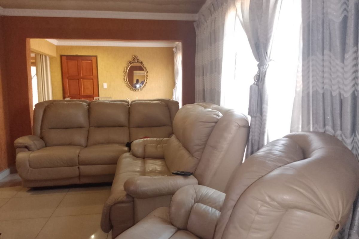A living room area featuring tiled flooring and coved ceilings, showing visible signs of water damage on the ceiling.