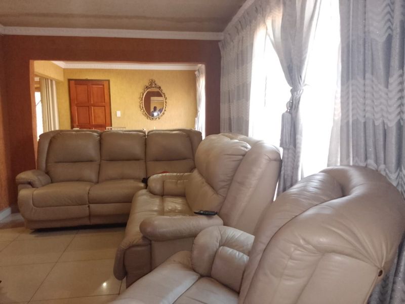 A living room area featuring tiled flooring and coved ceilings, showing visible signs of water damage on the ceiling.