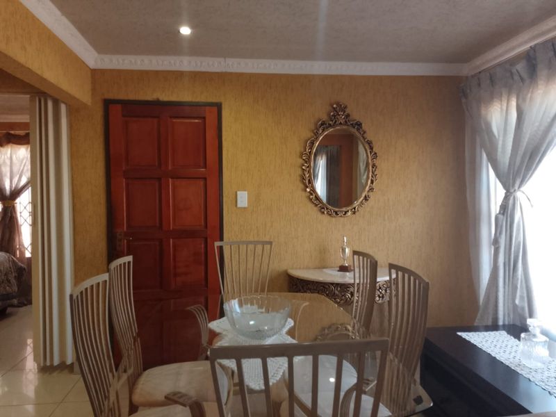 A dining room featuring textured wallpaper, decorative ceiling cornices, and tiled flooring, providing a traditional aesthetic.