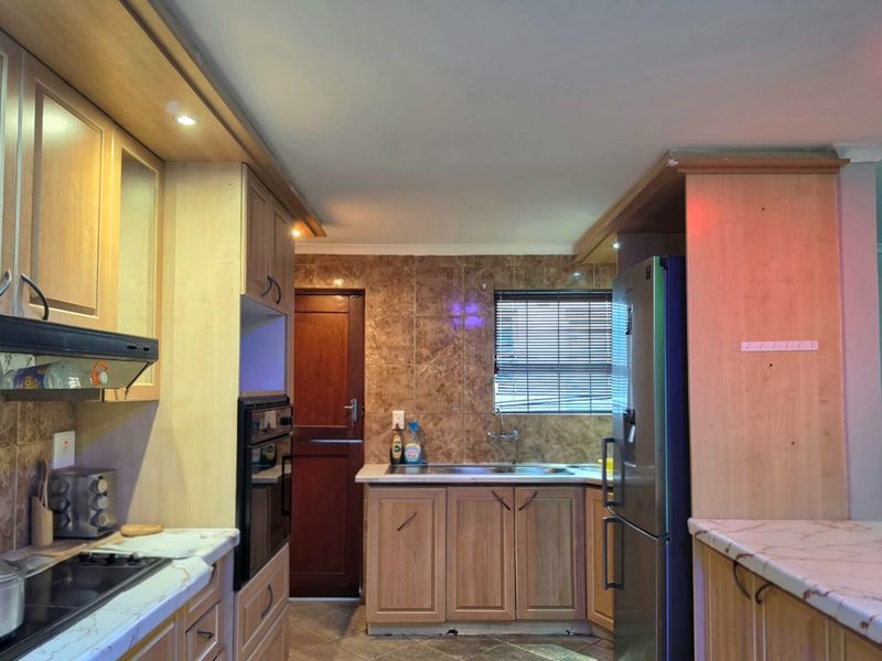 A functional kitchen featuring wood-tone cabinetry, laminate countertops, a tiled backsplash, and integrated appliances, offering a practical layout with potential for modern updates.