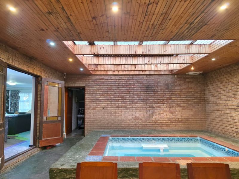 Indoor pool area featuring exposed brick walls, a timber-clad ceiling with a large skylight, and recessed lighting, offering a unique entertainment space.