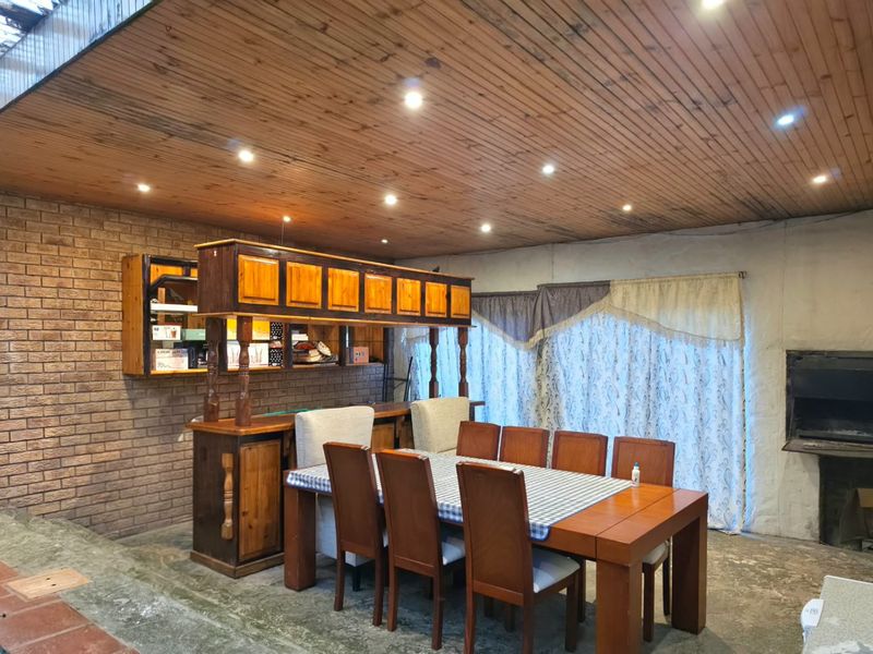 Spacious living area featuring a built-in bar, exposed brick wall, timber ceiling with recessed lighting, and a built-in fireplace.