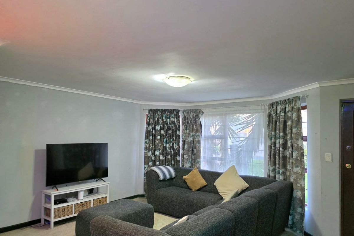 A living room featuring a large window with curtains, ceiling cornice, and a central flush mount light fixture.