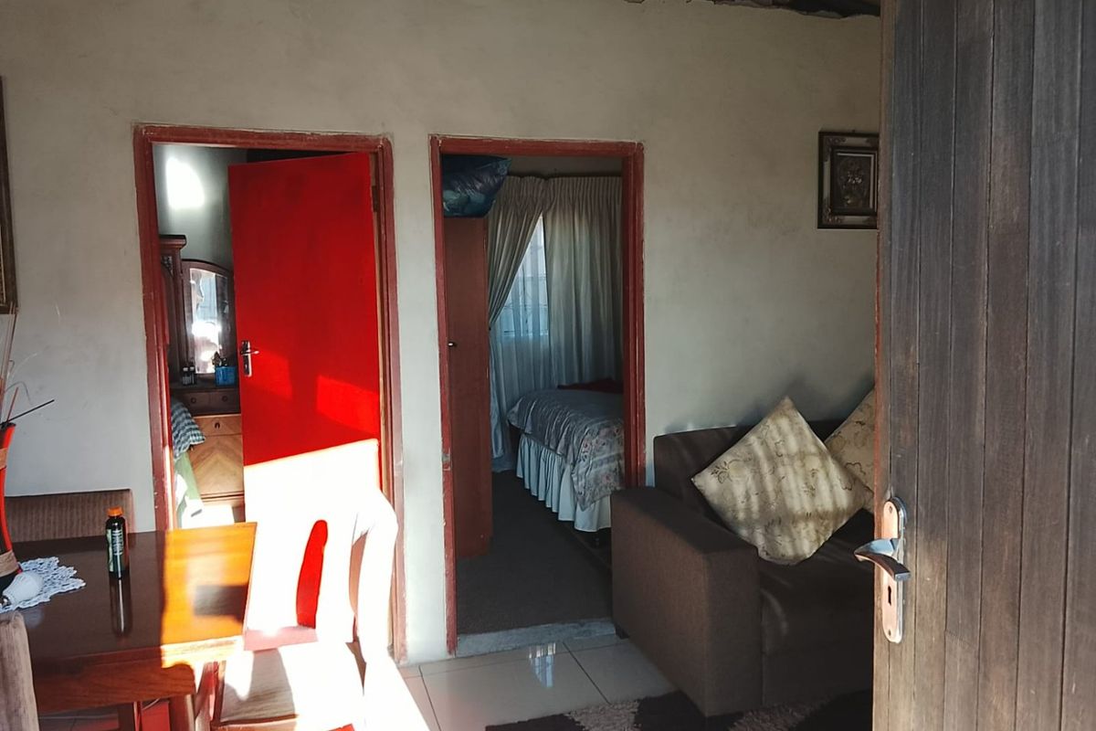 A living area featuring tiled floors and direct access to adjacent bedrooms, showing signs of unfinished wall and ceiling detailing.