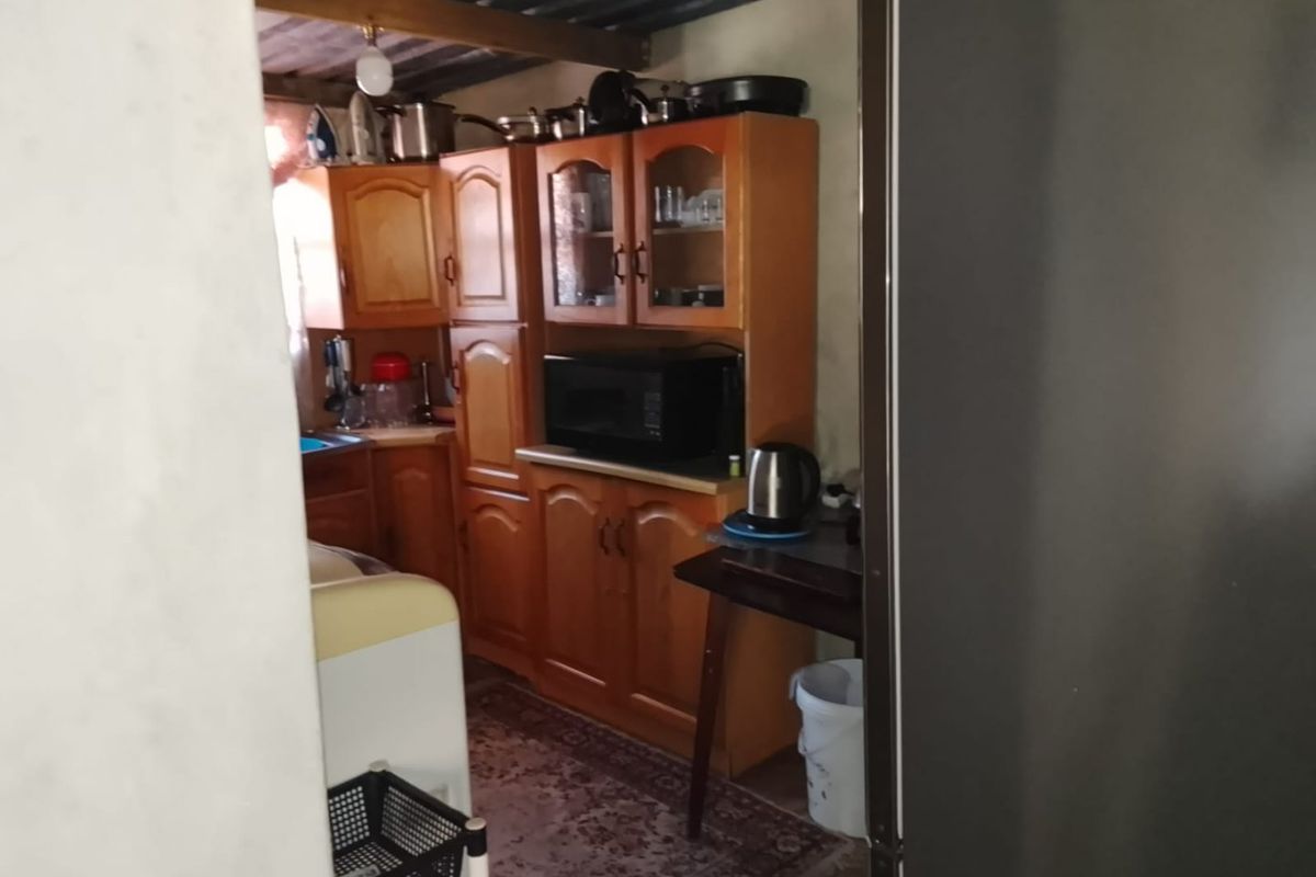 A compact kitchen featuring traditional wooden cabinetry and laminate countertops, currently showing signs of age and requiring cosmetic updates.