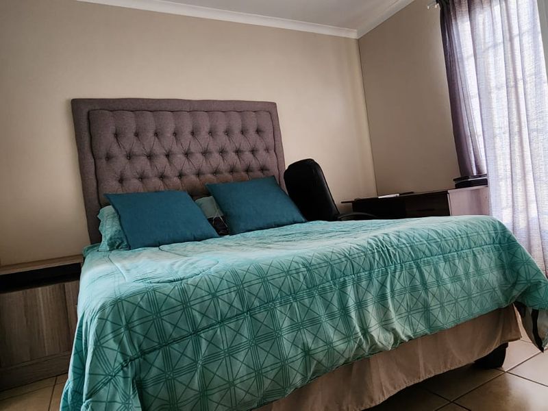 A bedroom featuring tiled flooring and an adjacent en-suite area with a pedestal basin.